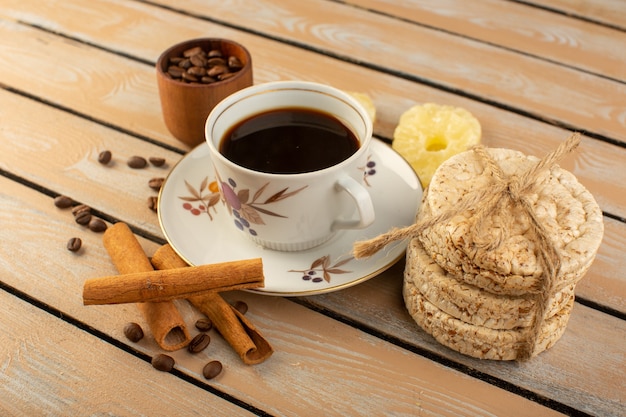 Une vue de face tasse de café chaud et fort avec des graines de café brun frais cannelle et craquelins sur le bureau rustique crème café graine photo grain