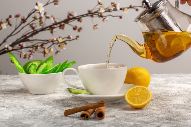 Vue de face tasse de thé aux citrons et cannelle sur la surface blanc clair