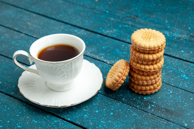 Photo gratuite vue de face tasse de thé avec des biscuits sur biscuit biscuit au sucre thé bleu bureau rustique