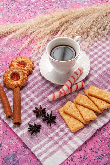 Vue de face tasse de thé avec des biscuits à la cannelle et des craquelins sur le bureau rose biscuit sucre sweet bake