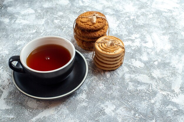 Vue de face tasse de thé avec des biscuits sur fond clair