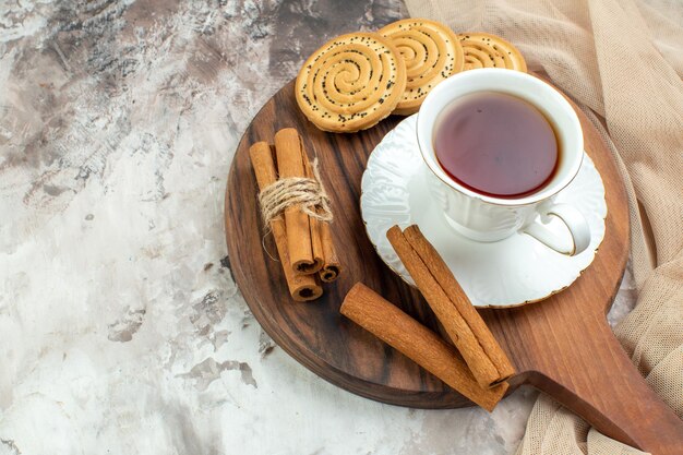 Vue de face tasse de thé avec des biscuits sucrés sur fond clair cérémonie de pause biscuits couleurs de tarte au café au sucre