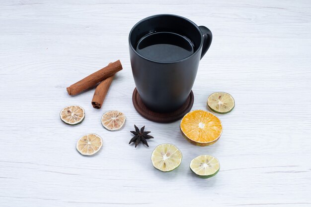 Vue de face tasse de thé avec du citron et de la cannelle sur un bureau léger