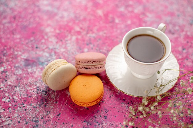 Photo gratuite vue de face tasse de thé à l'intérieur de la tasse sur la plaque avec des macarons français sur le bureau rose
