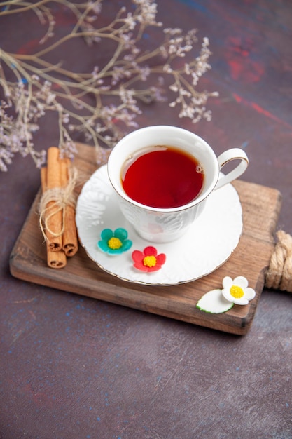 Vue de face tasse de thé à l'intérieur de la tasse en verre avec assiette sur l'espace sombre