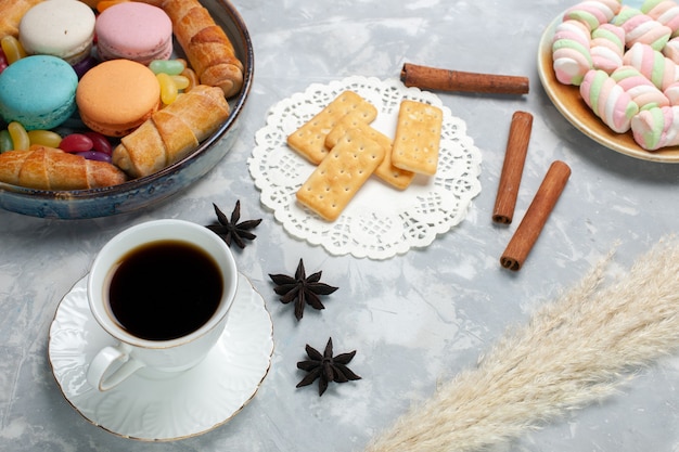 Vue de face tasse de thé avec des macarons et des bagels sur blanc