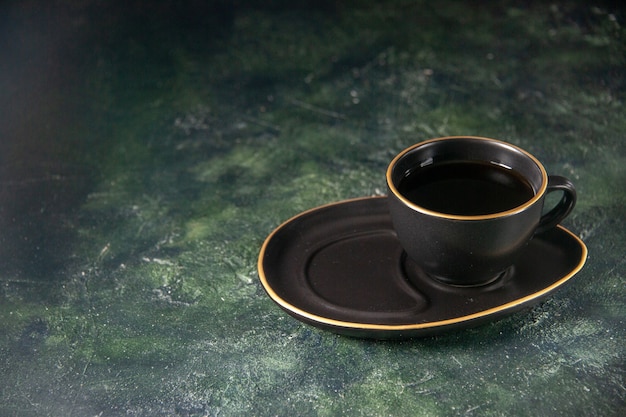 Vue de face tasse de thé en noir tasse et assiette sur surface sombre cérémonie du sucre en verre petit-déjeuner gâteau dessert couleur bonbons