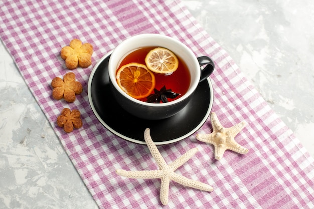 Vue de face tasse de thé avec des tranches de citron sur un bureau blanc