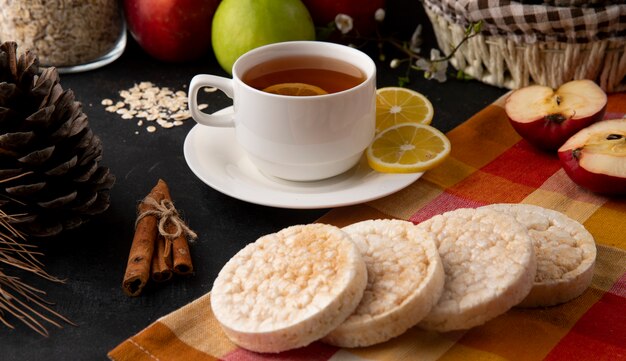 Vue de face tasse de thé avec des tranches de citron et de cannelle avec des pommes sur la table