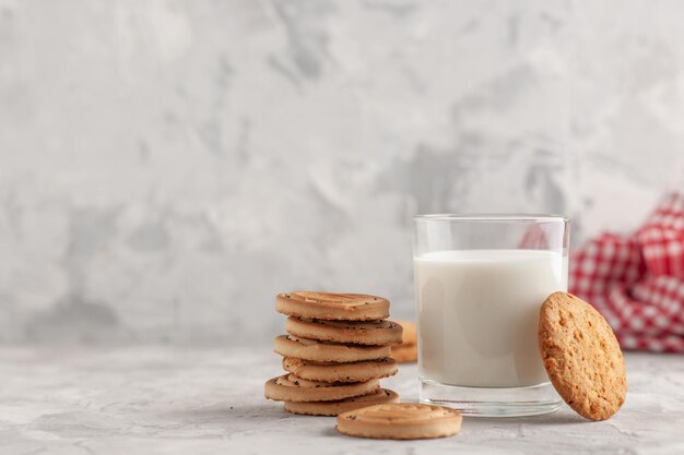 Vue de face d'une tasse en verre remplie de lait et de biscuits serviette dépouillée rouge sur le côté gauche sur fond blanc taché