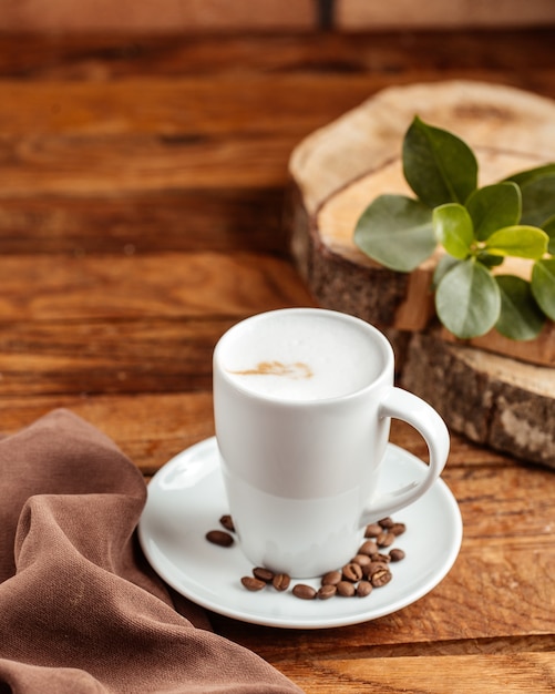 Une vue de face tasse vide blanche avec des graines de café brun sur la table en bois brun graine de tasse de café