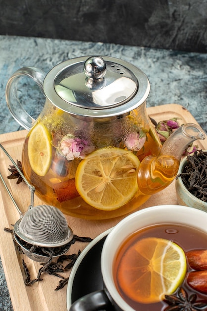 Vue de face thé au citron dans une tasse et une bouilloire sur le fond gris cérémonie du petit-déjeuner aux fruits couleur photo du matin nourriture