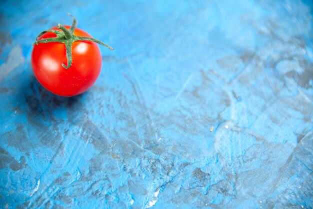 Vue de face tomate rouge fraîche sur table bleue