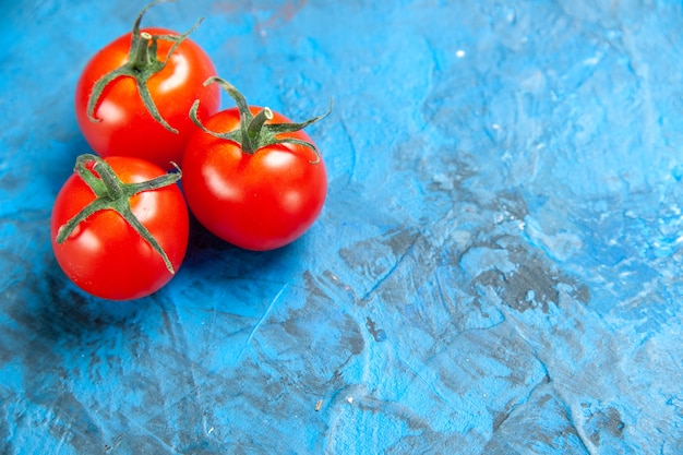 Vue de face des tomates fraîches sur la table bleue