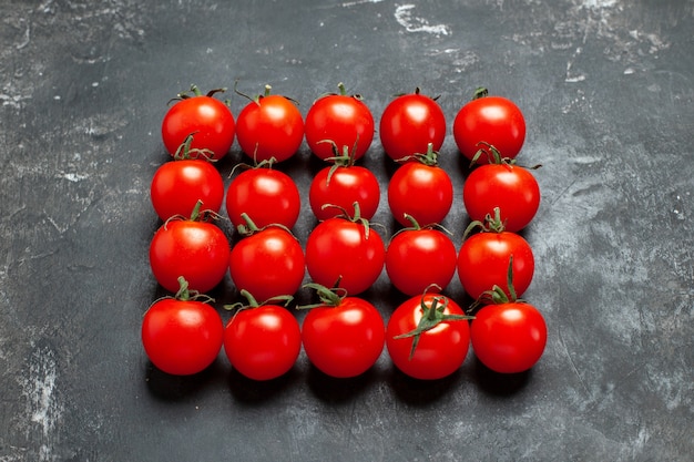 Vue de face de tomates rouges fraîches bordées d'une table sombre