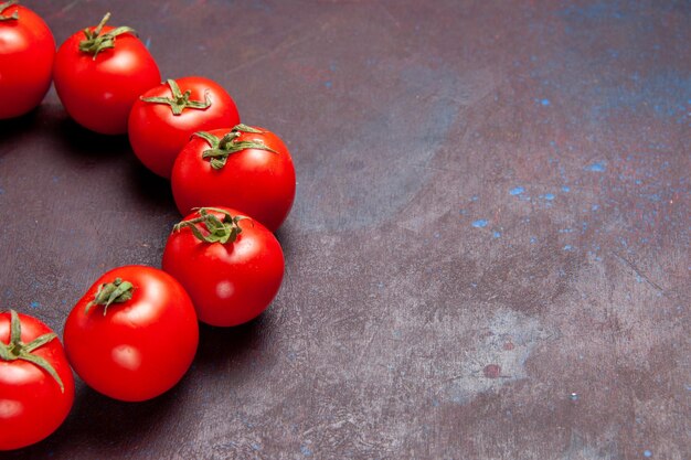 Vue de face des tomates rouges fraîches encerclées sur l'espace sombre