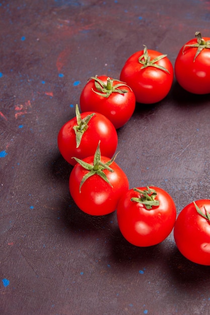 Vue de face des tomates rouges fraîches encerclées sur l'espace sombre