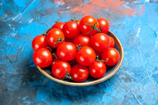 Vue de face des tomates rouges fraîches à l'intérieur de la plaque sur la table bleue