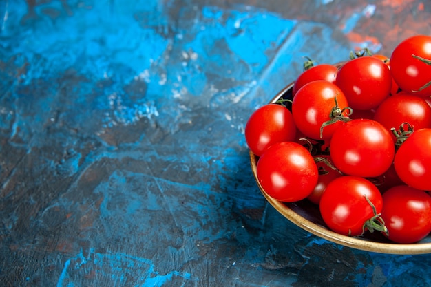 Vue de face des tomates rouges fraîches à l'intérieur de la plaque sur la table bleue