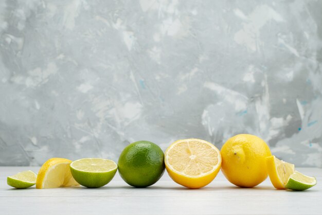 Vue de face en tranches de citron vert frais juteux et fruits aigres avec des citrons sur blanc