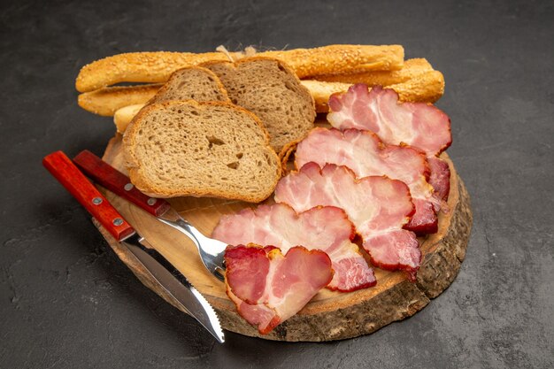 Vue de face des tranches de jambon frais avec des tranches de pain et des petits pains sur un repas de nourriture photo couleur de la viande de collation foncée