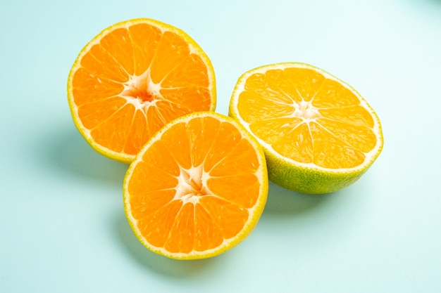 Vue de face des tranches de mandarine fraîches sur la table bleu clair
