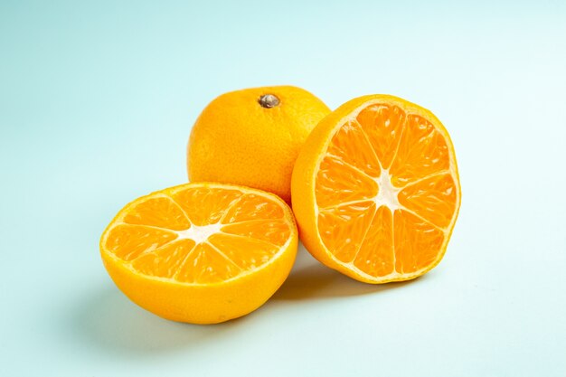 Vue de face des tranches de mandarine fraîches sur la table bleu clair