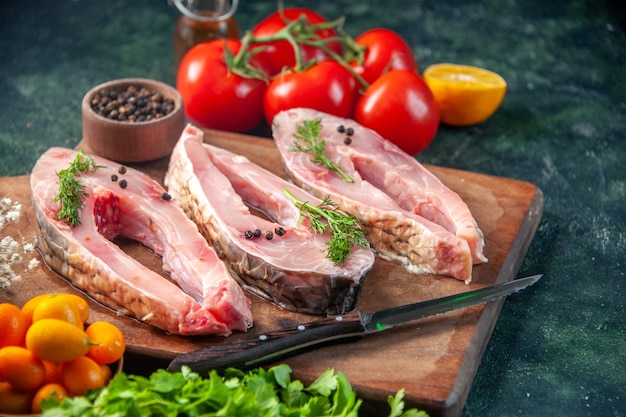 Vue de face des tranches de poisson frais avec des tomates et des verts sur la surface sombre des aliments santé poisson poivron couleur repas fruits de mer océan eau régime alimentaire salade