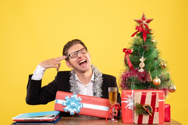 Vue de face travailleur masculin assis et célébrant Noël