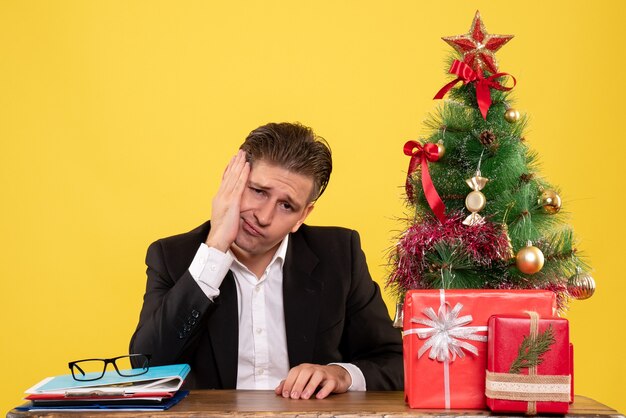 Vue de face travailleur masculin assis derrière sa table de travail