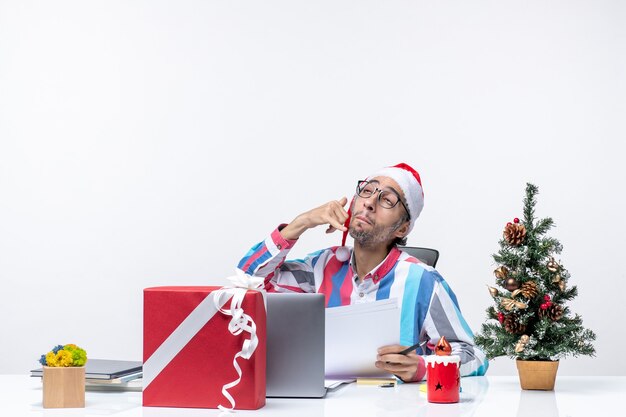 Vue de face travailleur masculin assis à sa place avec un ordinateur portable travaillant avec des documents émotion de bureau de travail de Noël