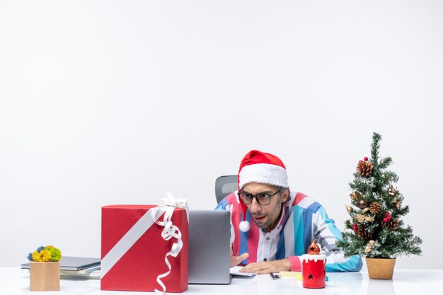 Vue de face travailleur masculin assis à sa place avec un ordinateur portable en l'utilisant émotion bureau travail de Noël
