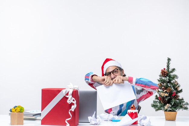 Vue de face travailleur masculin assis sur son lieu de travail déchirant des documents travail d'entreprise vacances de bureau de Noël