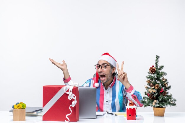 Vue de face travailleur masculin assis sur son lieu de travail se réjouissant du travail d'émotion d'affaires de Noël