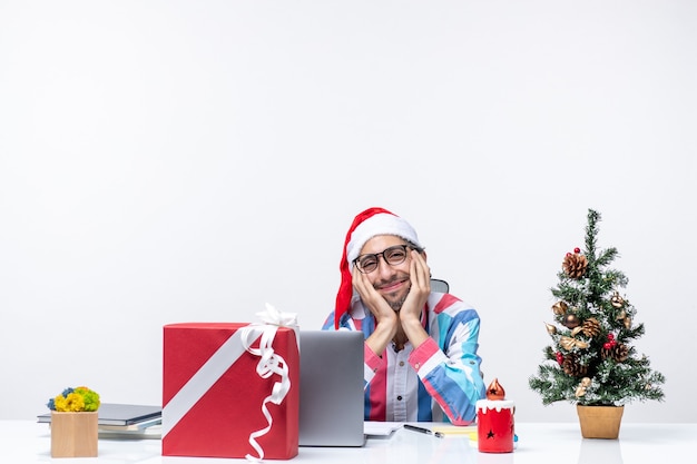 Vue de face travailleur masculin assis sur son lieu de travail se sentant fatigué souriant émotion de travail d'entreprise de Noël