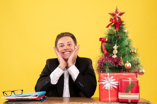 Vue de face travailleur masculin en costume assis derrière sa table de travail