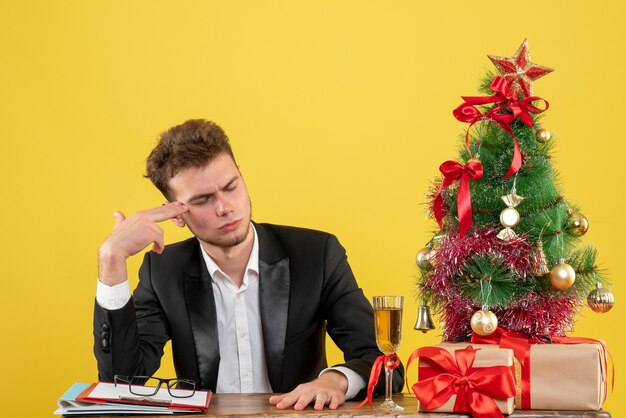 Vue de face travailleur masculin derrière son lieu de travail avec des cadeaux sur jaune