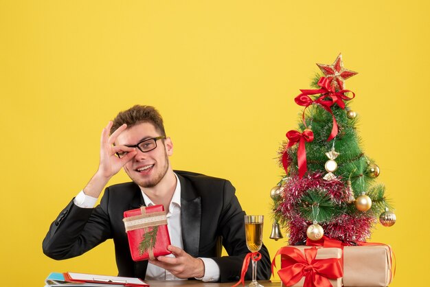 Vue de face travailleur masculin derrière son lieu de travail avec des cadeaux sur jaune