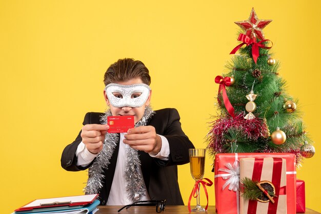 Vue de face travailleur masculin portant un masque de fête et tenant une carte bancaire