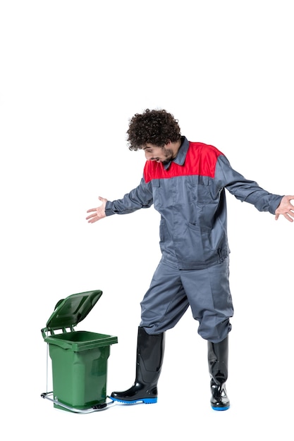 Photo gratuite vue de face d'un travailleur masculin en uniforme avec une petite poubelle sur un mur blanc