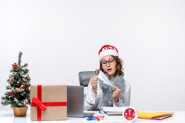 Vue de face travailleuse assise devant son lieu de travail jouant avec des avions en papier