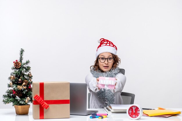 Vue de face travailleuse assise devant son lieu de travail tenant peu de présent