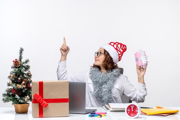 Vue de face travailleuse assise devant son lieu de travail tenant peu de présent