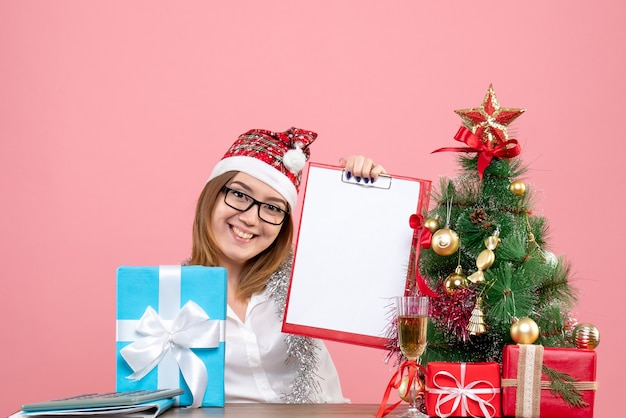 Vue de face de la travailleuse assise et tenant la note autour des cadeaux sur rose