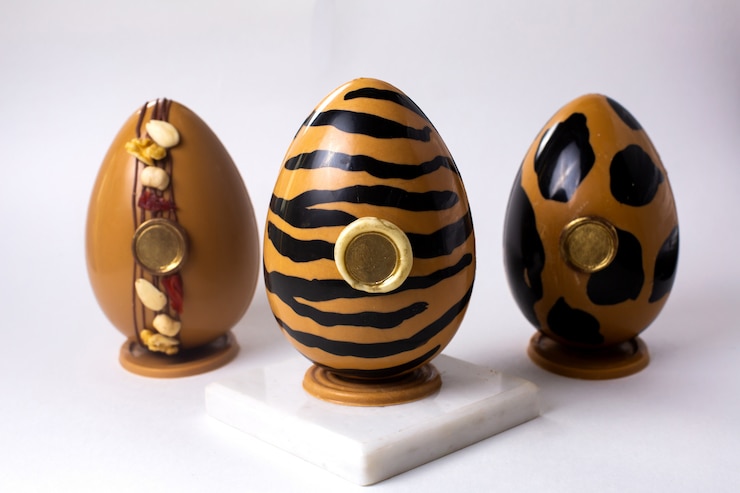 Photo gratuit vue de face trois œufs en chocolat en or et noir en couleurs tigre et léopard en or sur socle