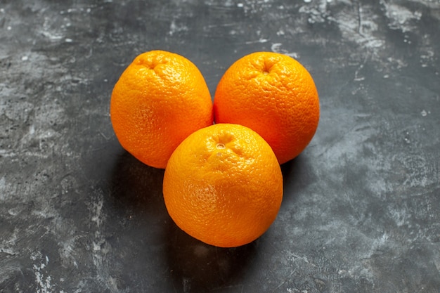 Vue de face de trois oranges fraîches biologiques naturelles sur fond sombre