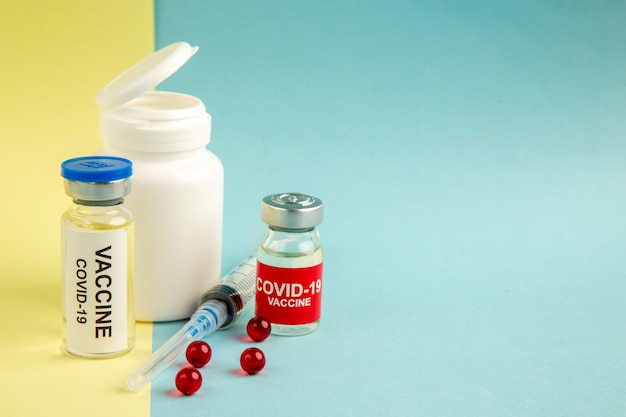 Vue de face des vaccins contre le coronavirus avec injection sur fond jaune-bleu virus de l'hôpital de laboratoire covid- science santé pandémie couleur endroit sans médicament