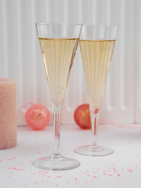 Vue de face de verres de champagne et de globes roses