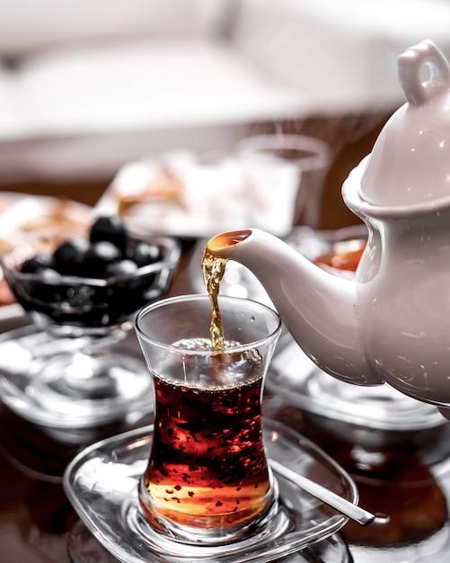 Vue de face verse du thé dans un verre d'armudu d'une bouilloire à thé