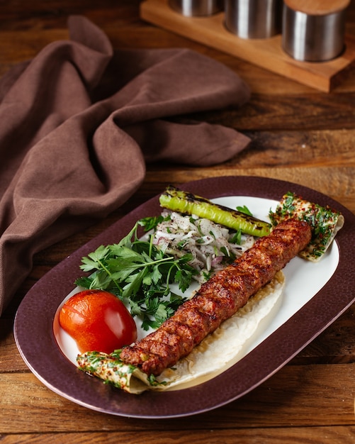 Une vue de face de la viande frite avec les verts d'oignon et la tomate sur le bureau en bois brun repas repas viande viande